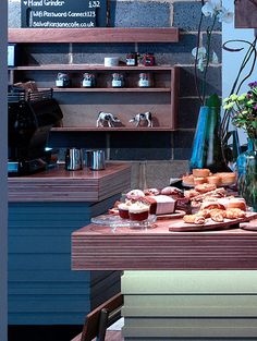 a table topped with lots of pastries on top of wooden shelves next to flowers