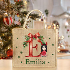 a personalized christmas shopping bag sitting on a table in front of a decorated christmas tree