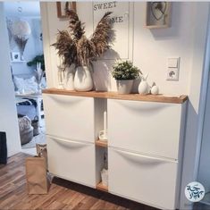 two white vases sitting on top of a wooden shelf in front of a door