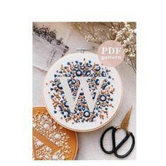 a cross stitch pattern with scissors next to it and some other crafting supplies on the table