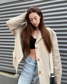 a woman with long brown hair wearing a jacket and jeans