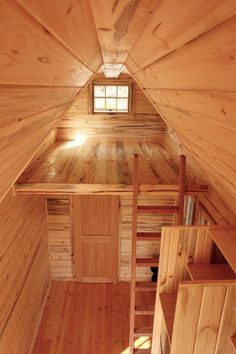 the inside of a small cabin with wooden floors and walls, looking down into the loft