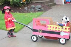 two children are playing with a toy firetruck and cow on the sidewalk in front of their house