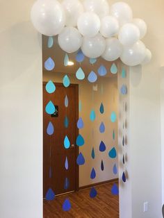 balloons and streamers are hanging from the ceiling in an office hallway with wood flooring