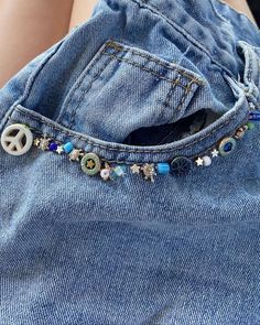 a peace sign is in the pocket of someone's jean jacket with beaded charms