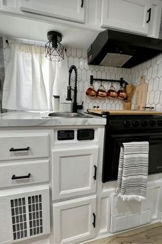 a kitchen with white cabinets and black stove top oven next to a counter that has towels hanging on it