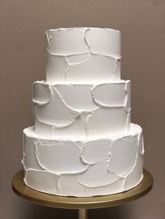 a three tiered white cake on a gold stand