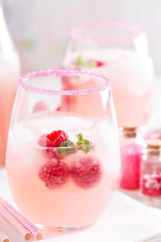 two glasses filled with raspberry lemonade on top of a white table cloth