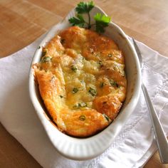 a casserole dish is sitting on a napkin with a fork and knife next to it