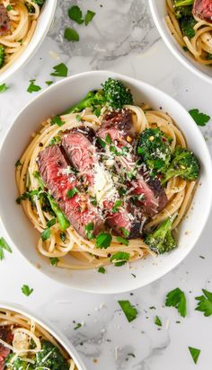 four white bowls filled with pasta, broccoli and meat on top of a marble table