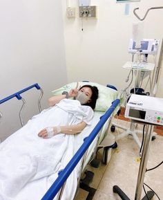 a woman laying in a hospital bed next to an iv machine