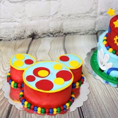 two mickey mouse themed birthday cakes sitting on top of a wooden table next to each other