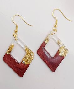 two square shaped red and white earrings with gold accents on the sides, one is hanging from