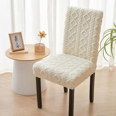 a white chair sitting next to a table with a potted plant on top of it