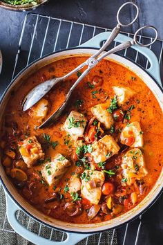 a large pot filled with stew on top of a metal rack next to a spoon