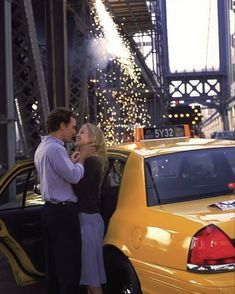 a man and woman standing in front of a taxi