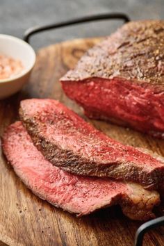 a steak on a cutting board with sauces and a fork next to the steak