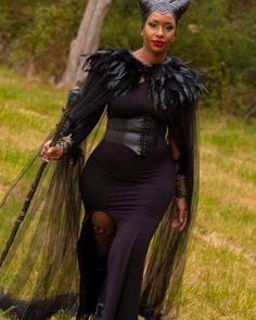 a woman in a black dress with feathers on her head and wings around her body