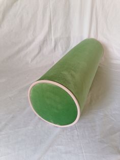 a green cone shaped object on a white sheeted surface with the end rolled up