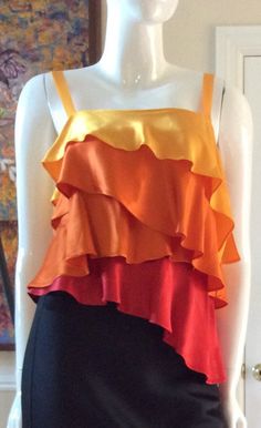 Vintage 1995 unworn satin four ruffle top by Moschino Couture. From my private museum quality unworn Moschino collection. Size 8 USA, Italian 42AsymmetricalYellow, two tones of orange, and red ruffles3/4” strapsSide zipper is hiddenVersatile pieceMeasurements:Bust - 34”Waist - 28”Hips - 40”Length - 20” - 24”This listing is for the top only Orange Silk Summer Tops, Summer Orange Silk Tops, Orange Silk Top For Summer, Yellow Sleeveless Silk Top, Multicolor Silk Tops For Evening, Orange Sleeveless Ruffled Top, Oc Dress, Moschino Couture, Orange Twist