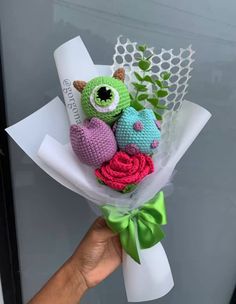 a hand holding a bouquet of crocheted flowers with an owl and bird on it