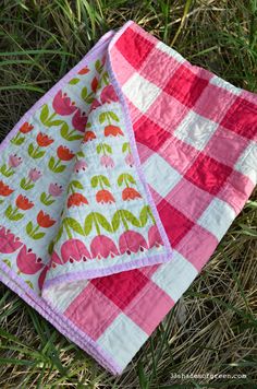 two pink and white quilts laying on the grass