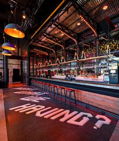 an empty bar with red chairs and neon signs on the floor in front of it