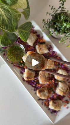 a white plate topped with meatballs and veggies next to a potted plant