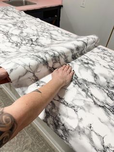 a person with their hand on the edge of a marble counter top that is being worked on