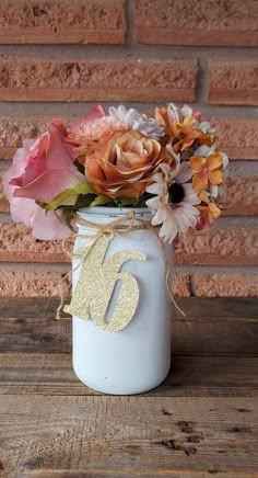 a white mason jar filled with flowers on top of a wooden table