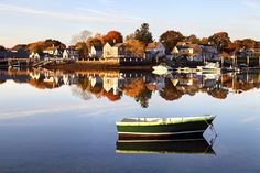 a small boat floating on top of a lake next to a shore filled with houses