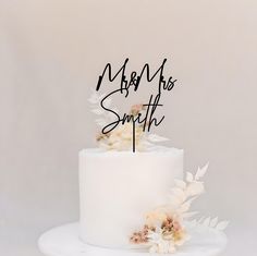 a white cake with flowers on top and the words mr and mrs smith written in cursive writing