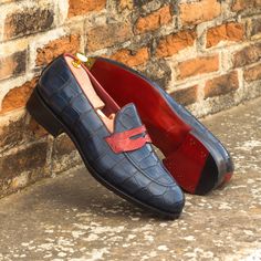 a pair of blue shoes sitting on top of a brick wall next to a red shoe