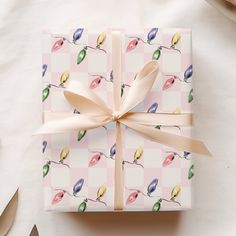 a gift wrapped in pink and green wrapping paper with a bow on top of it