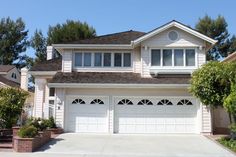 a large white house with two garages on the front and one above it's door