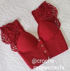 two red knitted bras laying on top of a white bed with lacy crochet