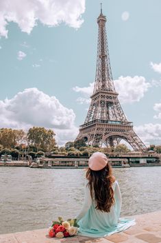 a woman sitting in front of the eiffel tower with her back to the camera