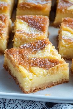 several pieces of cake sitting on a white plate with powdered sugar toppings around them