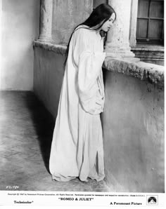 an old photo of a woman leaning against a wall with her back to the camera