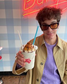 a young man holding up a cup of ice cream