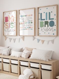 three framed pictures hang on the wall above a bench with storage bins underneath it