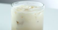 a close up of a drink in a glass on a table with a white background