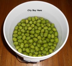 a white bowl filled with green olives on top of a wooden table