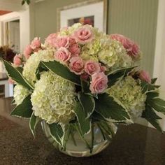 a vase filled with pink and white flowers on top of a counter next to a doorway