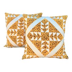 two yellow and white pillows with geometric designs on them, one in the shape of an arrow