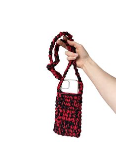 a hand holding a red and black cell phone case with a string attached to it