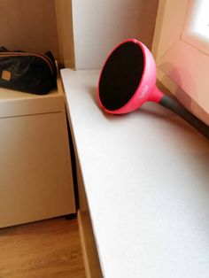 a pink hair dryer sitting on top of a counter next to a white cabinet