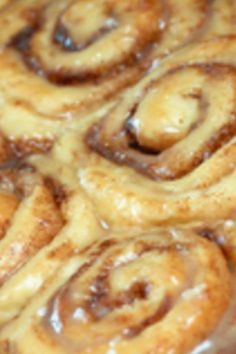 cinnamon rolls with icing sitting on top of a pan