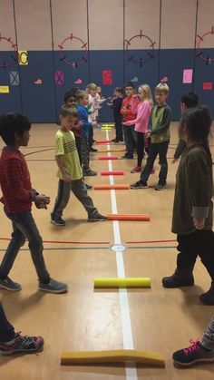 a group of children standing on top of a hard wood floor next to an obstacle course