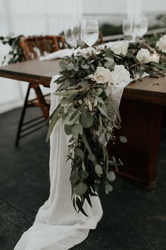 the table is set with white flowers and greenery